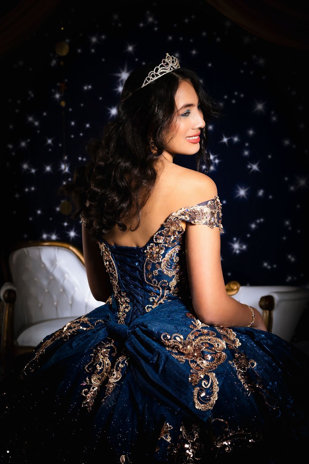 Back detail shot of a navy blue formal gown with intricate metallic embellishments.