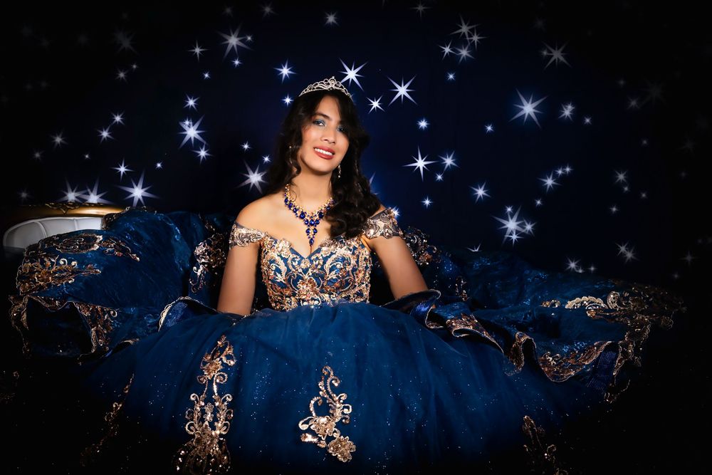 Ethereal photo of a deep blue formal dress with golden details under starry lights.