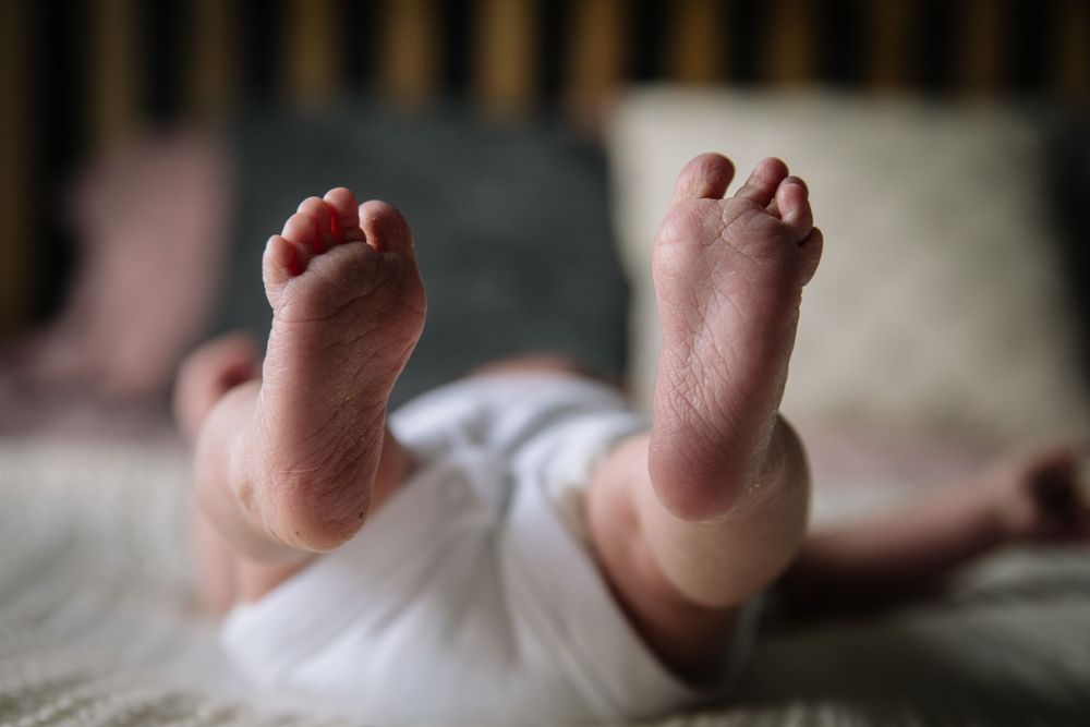 Close-up of tiny newborn baby feet against a light background.