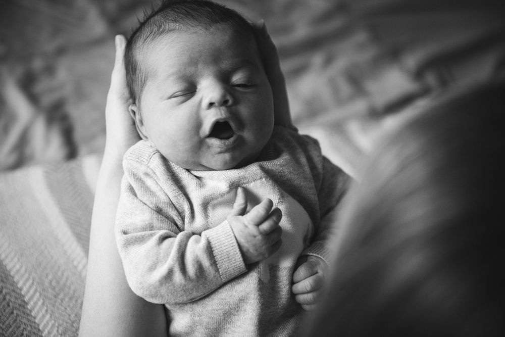 Black and white portrait of newborn baby in light colored onesie.