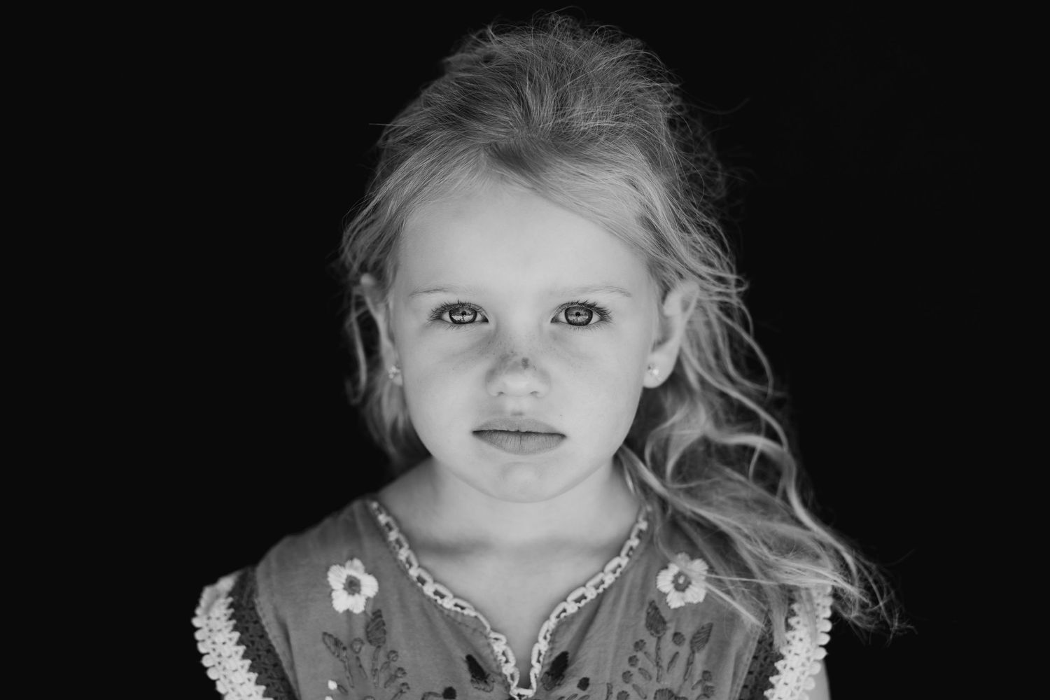 Close-up portrait showing soft lighting and delicate features against black backdrop.