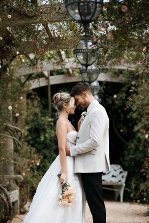 Wedding couple shares romantic moments under trees decorated with hanging lights.