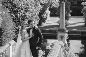 Wedding ceremony takes place on a sunny day in a lush garden setting.