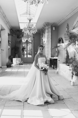 Elegant bridal portraits in a grand hallway with crystal chandeliers and flowing wedding dress.