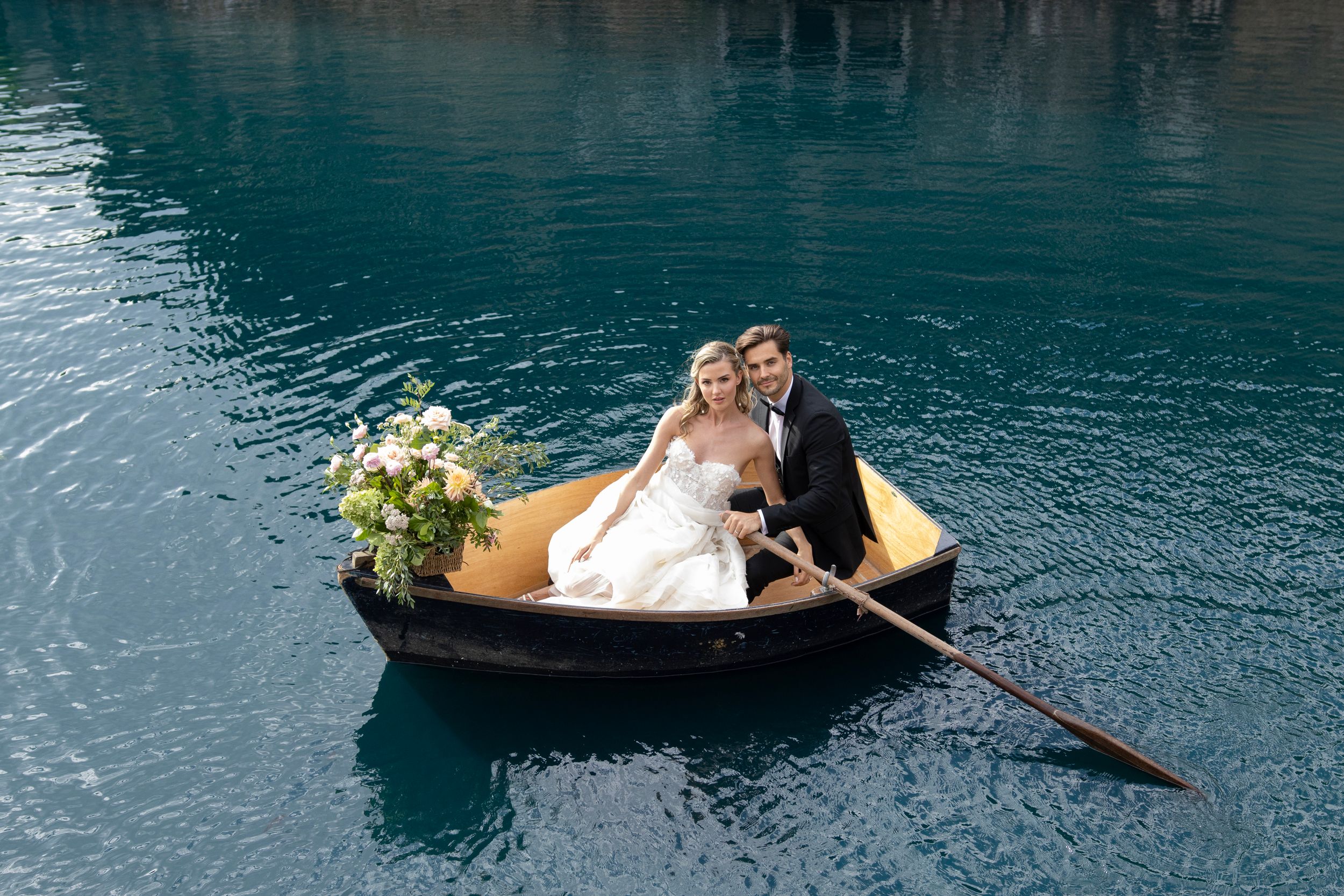 Romantic wedding photo session in wooden boats on serene blue waters.