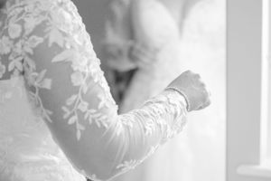 Detail shot of intricate white lace embroidery on wedding dress fabric.