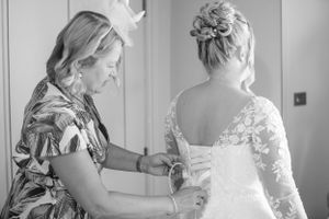 Black and white photo of wedding dress preparations in a sunlit room.