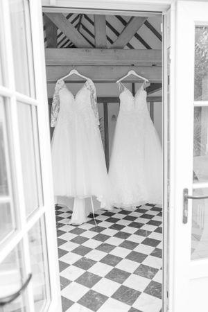 Wedding dresses hanging in a room with black and white checkered floor.