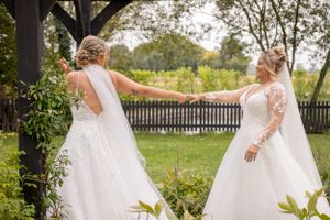Bridesmaids in orange dresses gather outdoors for playful group photos with the bride.