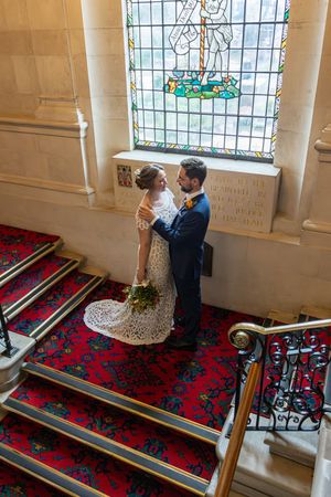 A wedding ceremony moment photographed on red-carpeted church stairs with stained glass windows.