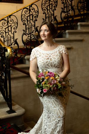 A wedding dress with detailed lace patterns is photographed near ornate iron railings.