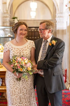 A tender moment captured in a church with beautiful stone archways and stained glass windows.