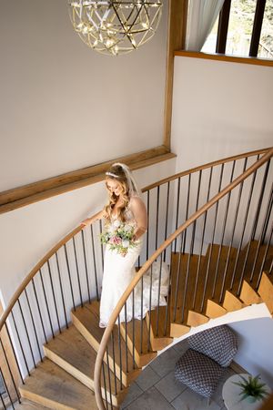 Elegant staircase with curved wooden railing and modern geometric chandelier.