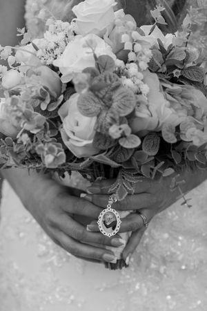 Close-up of bridal bouquet with white flowers and vintage jewelry details.