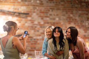 Wedding guests taking photos and celebrating at outdoor brick venue.
