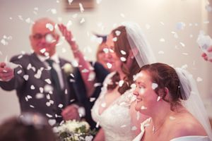 Wedding celebration with white confetti falling against a soft pink background.