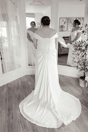 A white wedding dress displayed on a wooden floor in different angles.