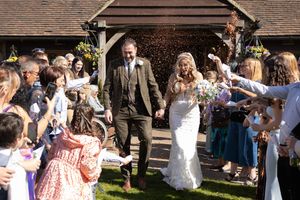 Wedding guests celebrate with arms raised during outdoor garden reception.