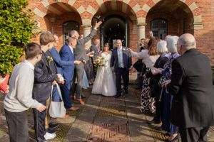 Wedding guests mingling outside brick archway entrance.
