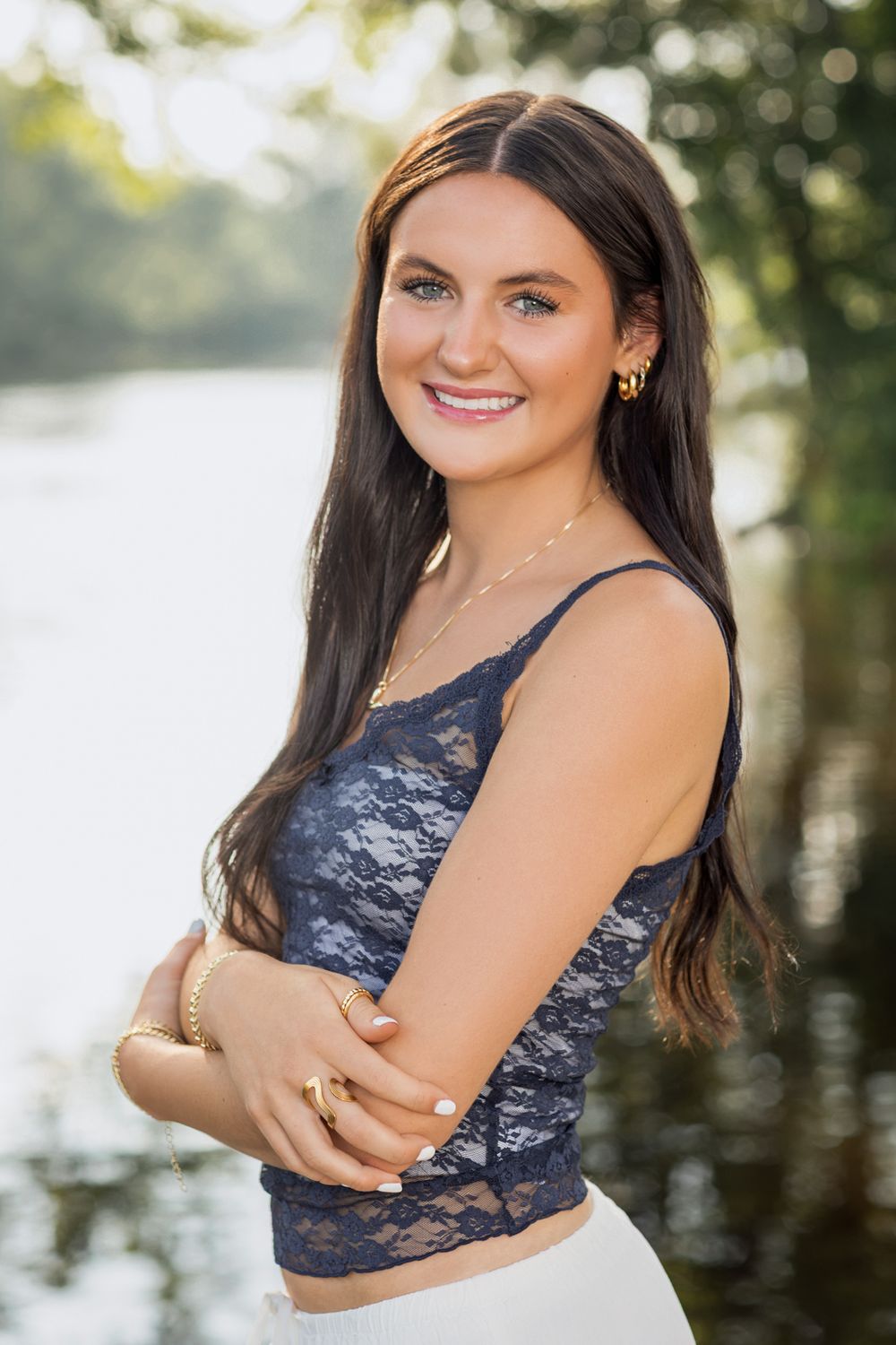 Portrait of person in navy lace top smiling by waterfront.