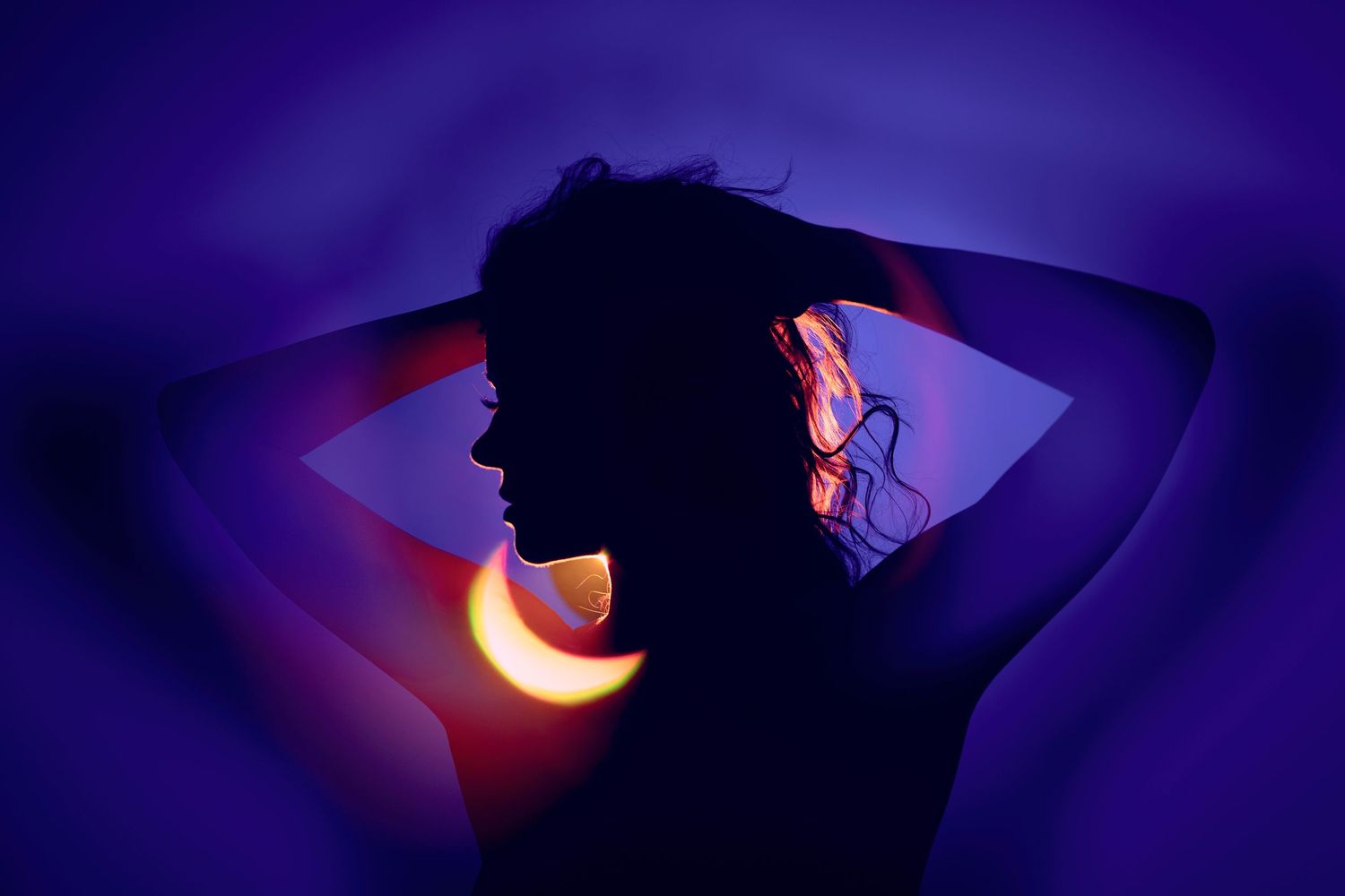 Silhouette portrait with neon lighting effects against purple background.