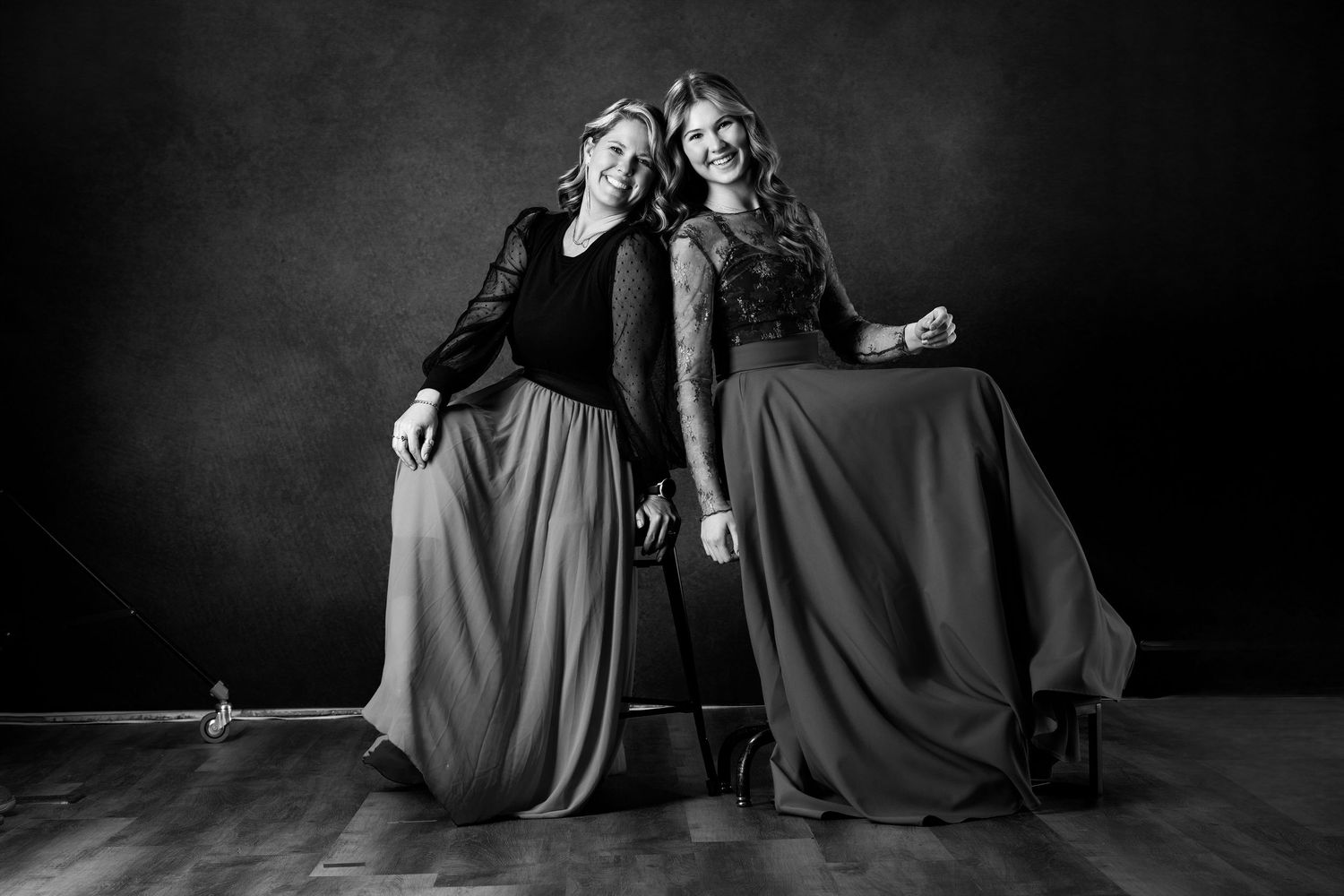 Two people in flowing dark dresses pose dramatically in black and white studio portrait. branding North Platte Nebraska Photographer