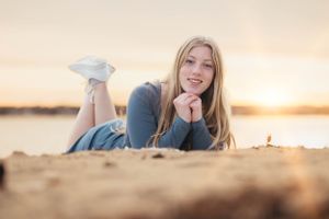 Woman lying on beach sand during golden hour sunset.