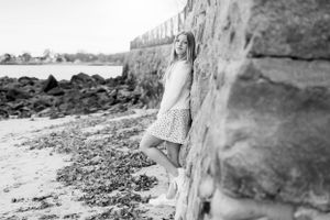 Black and white portrait by stone wall on rocky beach shoreline.