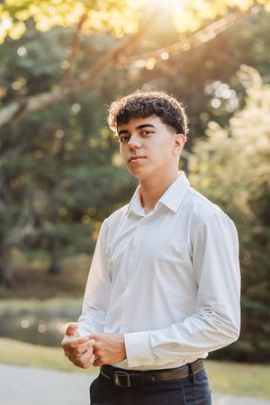 Portrait of person in formal white shirt and dark pants in sunset garden setting.