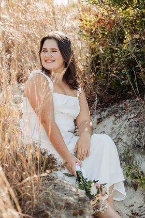 Natural outdoor portrait sitting on sand with dried grass and berries in background.