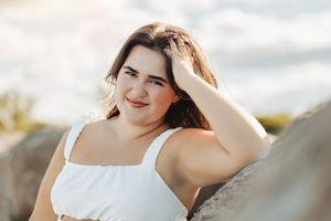 Close-up outdoor portrait with natural lighting against cloudy sky.