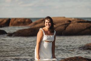 Summer portrait on coastal rocks with ocean and cliffs in background.