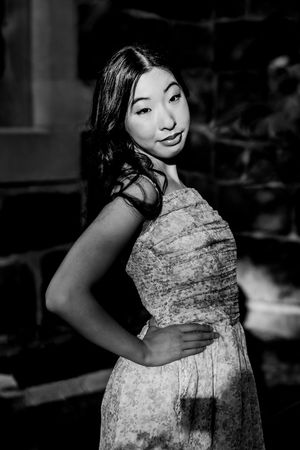 Black and white photo series showing a woman in a patterned dress posing expressively against a dark background.