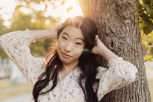Outdoor portrait session at golden hour with a white floral dress against a sunlit natural background.