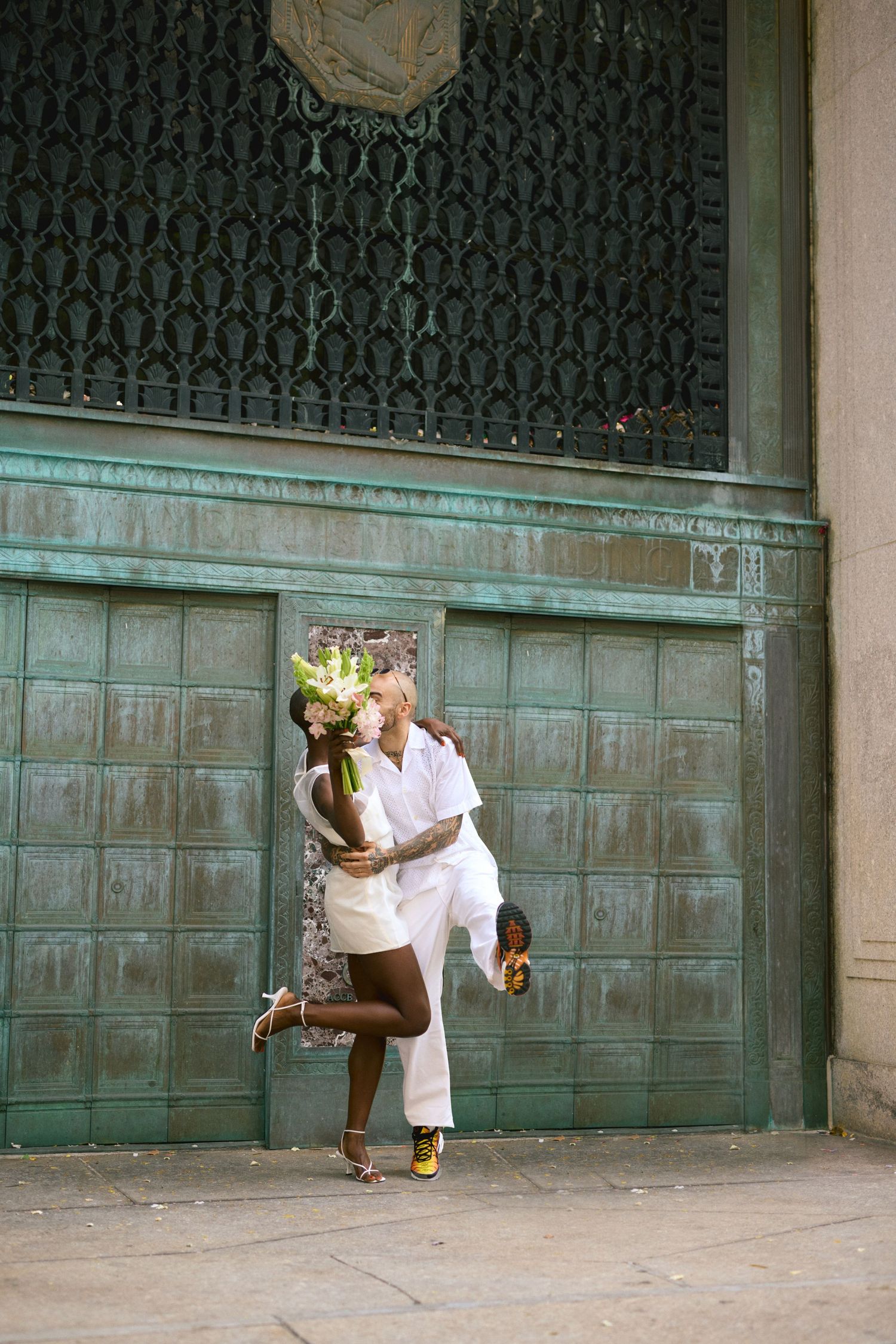 A romantic moment captured of a couple eloping, embracing in front of a weathered turquoise door at New York City Hall.