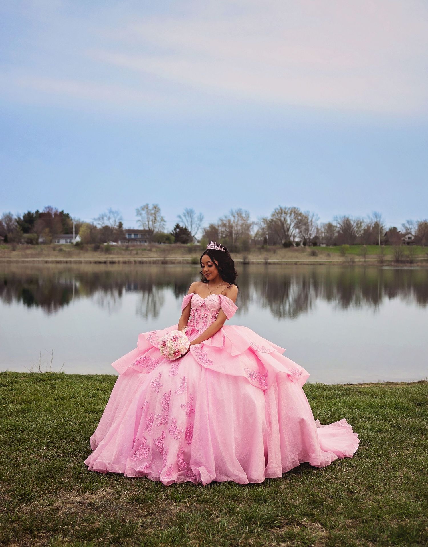 A flowing pink princess gown creates an elegant scene by a peaceful lake.