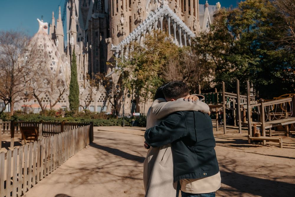 Couple hugging with basilica peeking through trees Sagrada Família Surprise proposal photoshoot Barcelona BarcelonaLoversPH