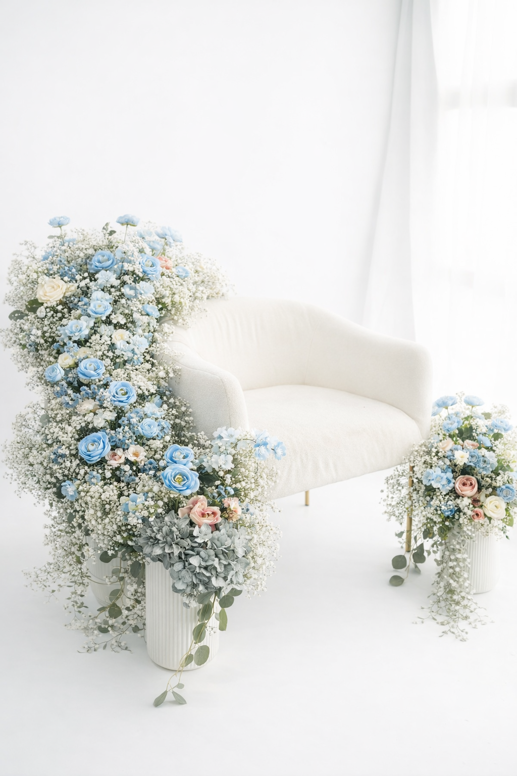 Delicate blue roses and baby's breath flowers arranged in white ceramic vases against a bright white background.