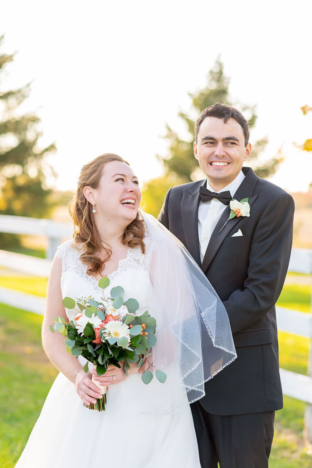 A bride and groom share joyful candid moments during their sunset wedding photoshoot outdoors.