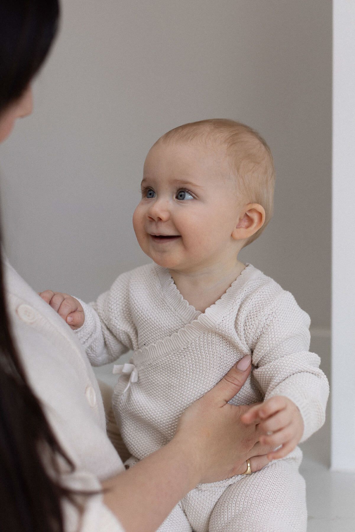 Smiling baby looking up at her mother who is holding her, photographed during an in home session in Brighton