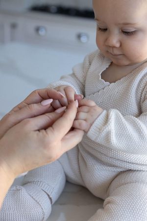 Close up image of baby holding and looking at her mothers hands during a family photography session in Brighton