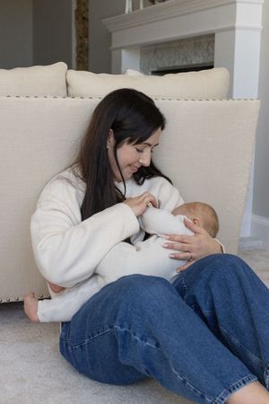Mother sitting on the floor breastfeeding her baby during a family photography session in Brighton