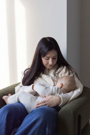 Mother sitting in a chair breastfeeding her baby during a family photography session in Brighton