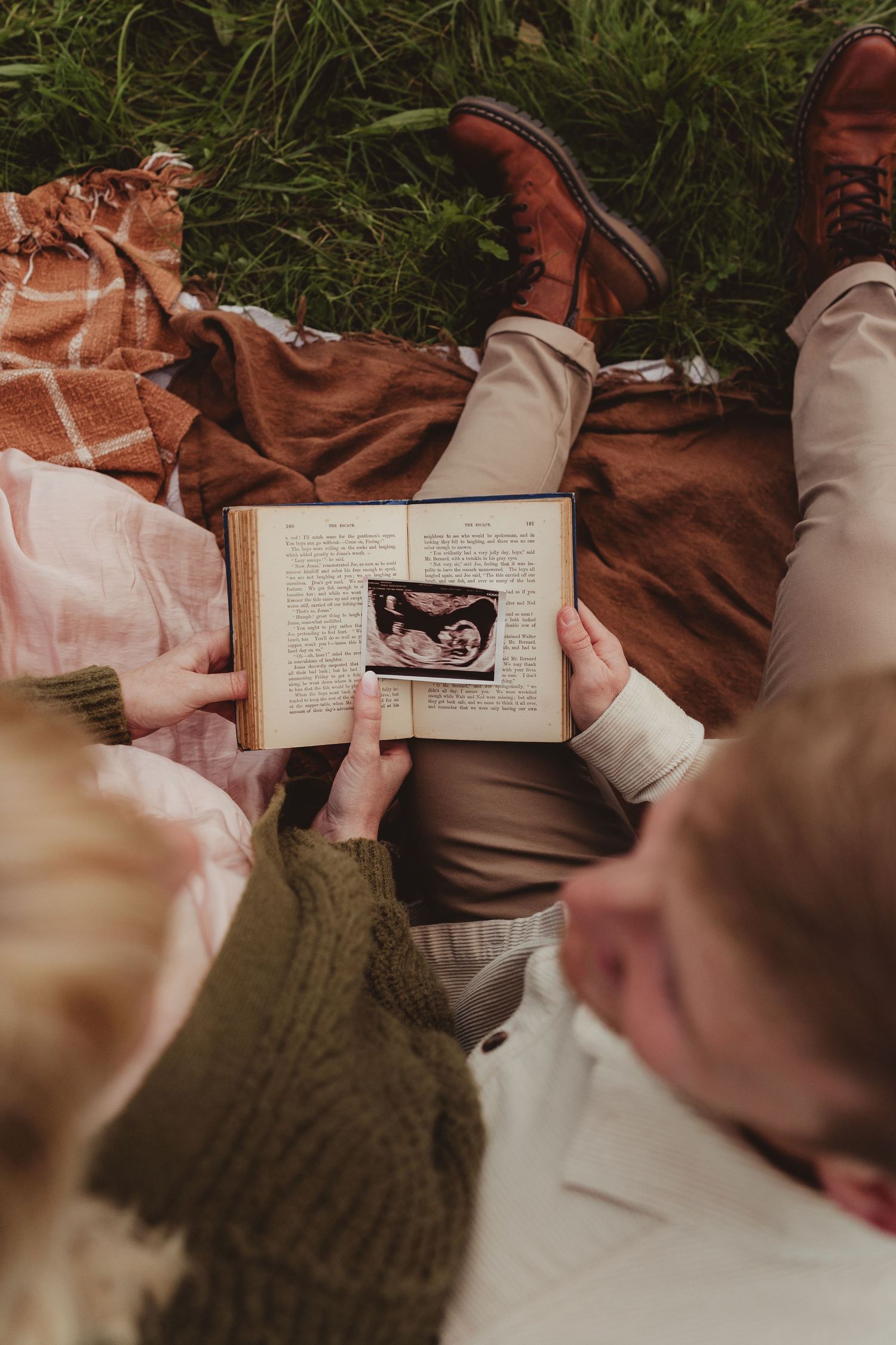 A couple shares tender moments in a wildflower field wearing neutral tones during a maternity photo session.