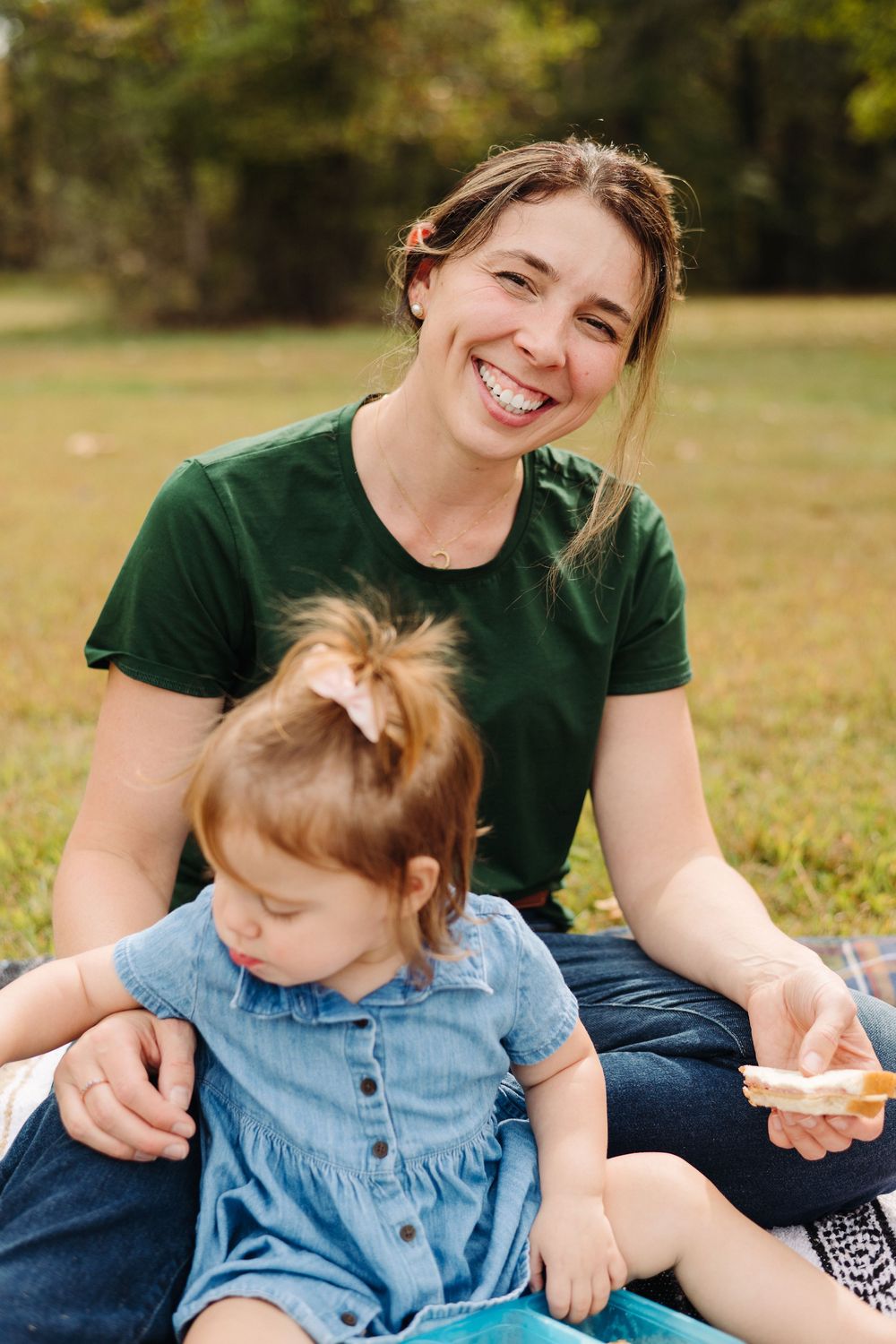 Joyful outdoor moments captured on a blanket in a grassy field during a sunny day.