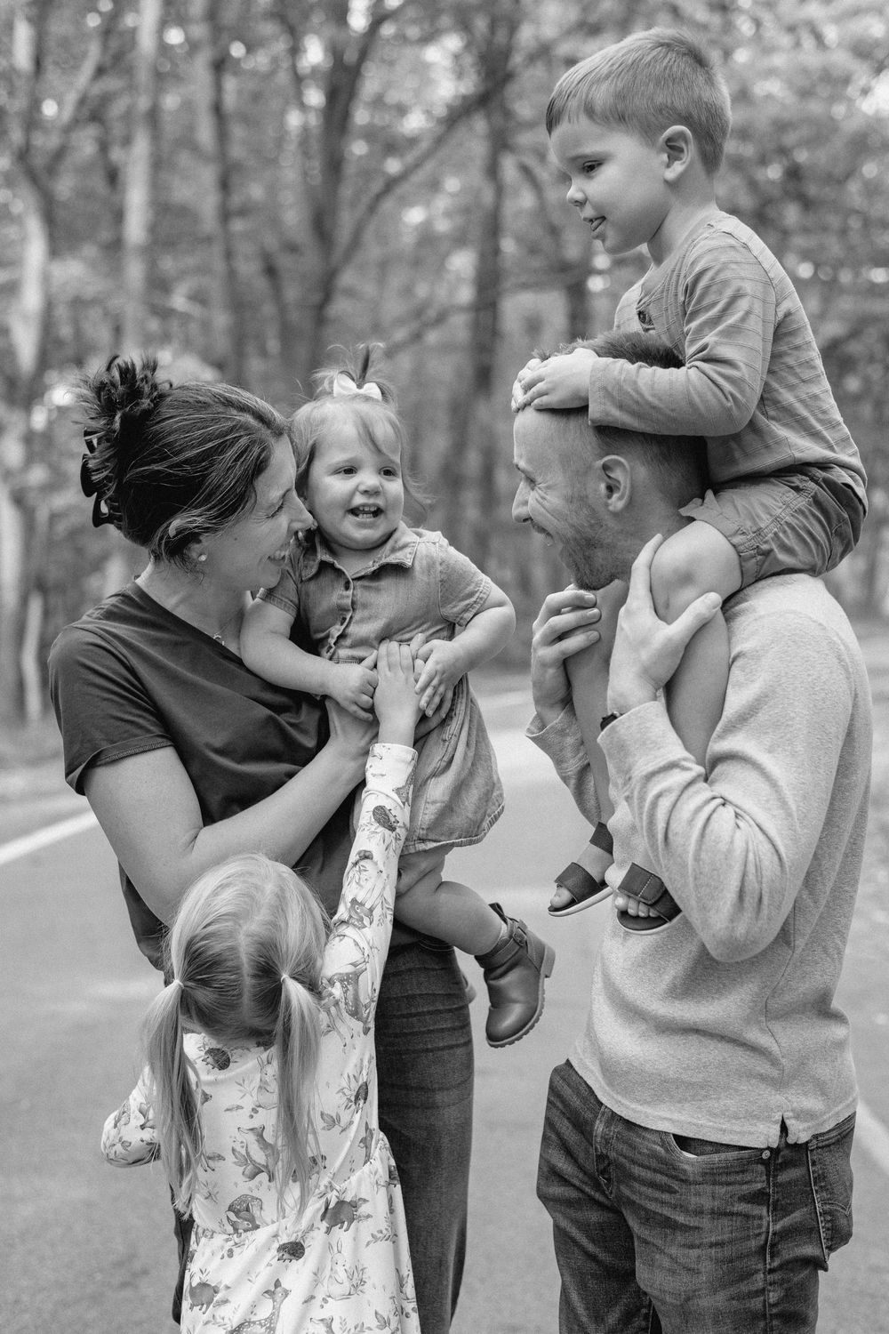 A series of playful black and white photos showing joyful embraces and laughter in an outdoor setting.