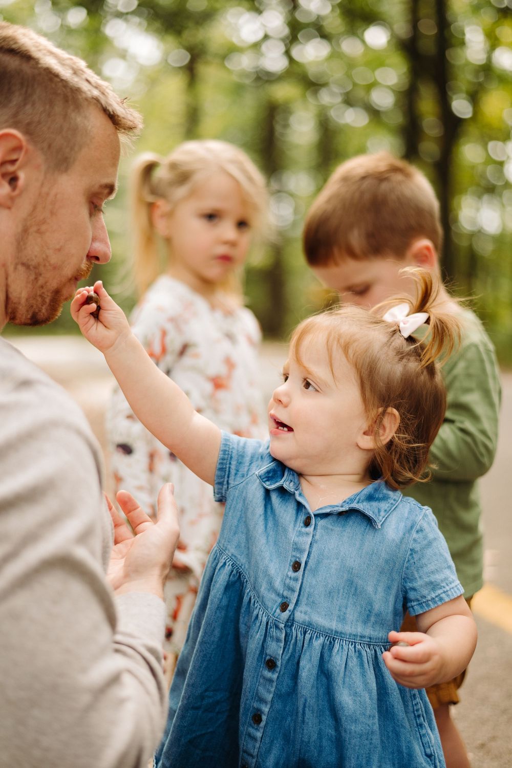 A heartwarming family moment captured in a forest setting with children and an adult sharing a playful interaction.