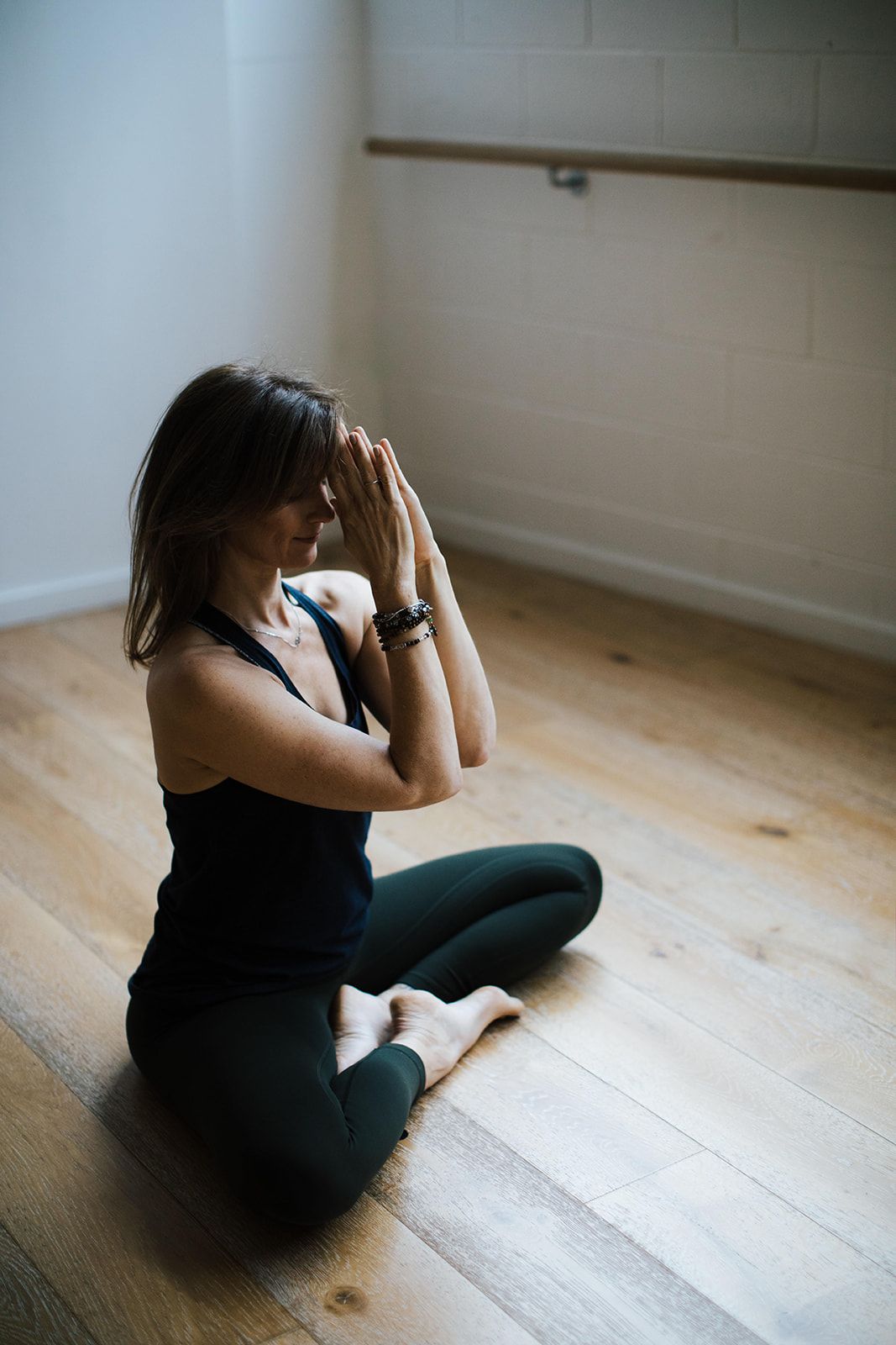 A person in dark clothing sits on a wooden floor against a white wall in a series of progressive emotional poses.