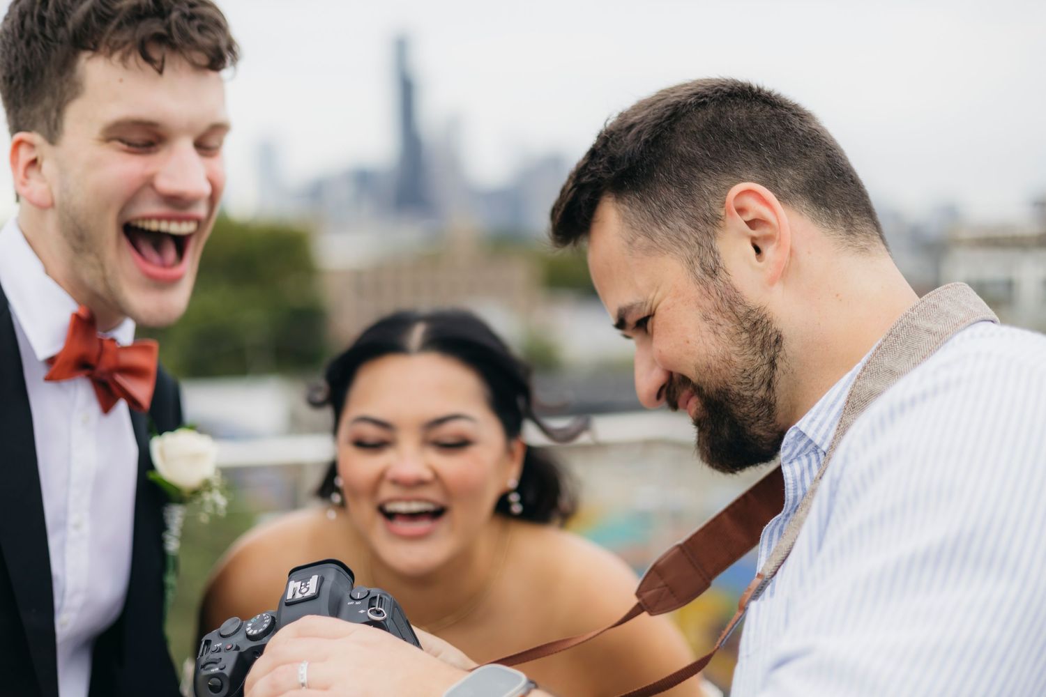 Chicago wedding photographer shows camera to the newlyweds with city skyline visible in the background.