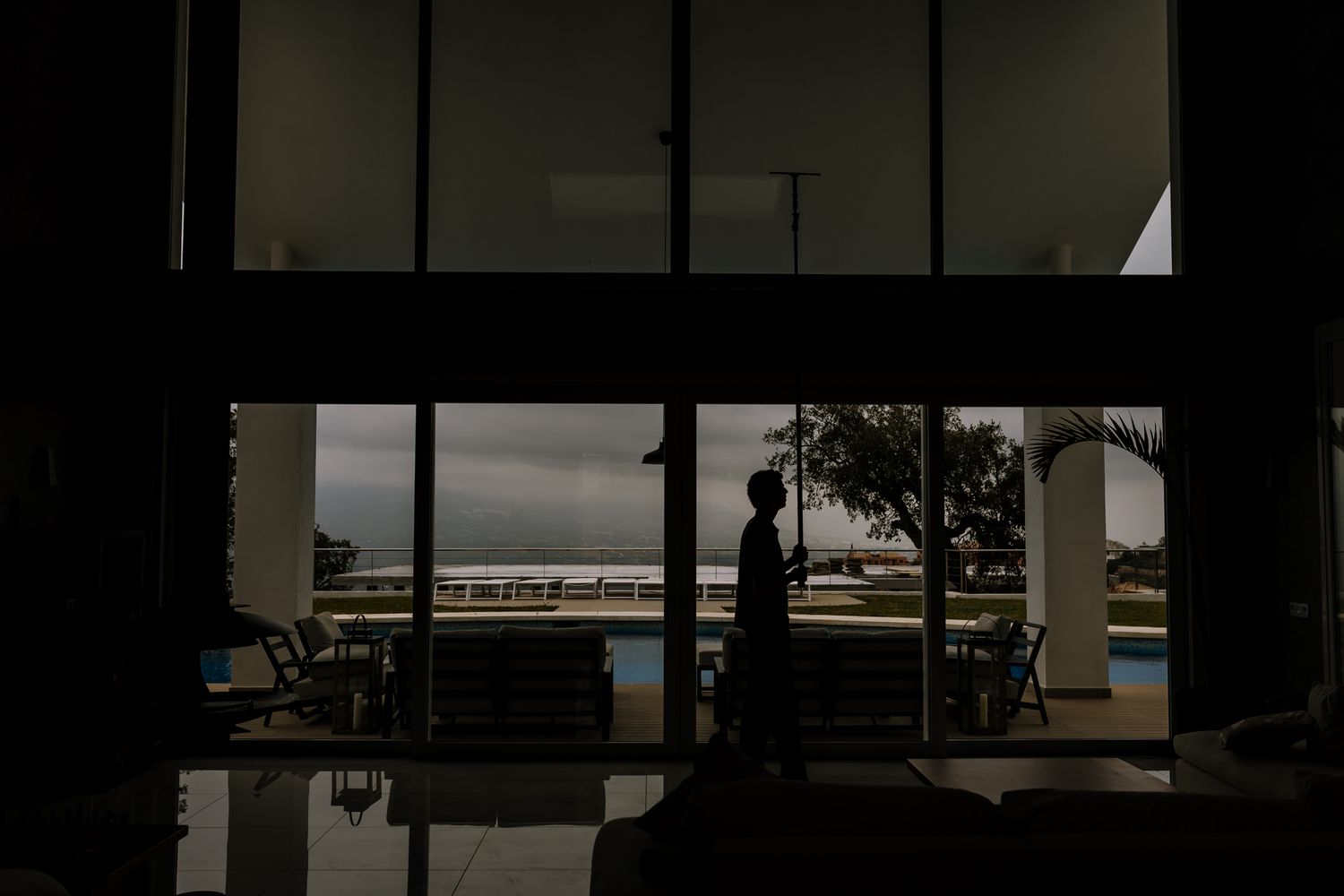 A silhouette of Tom cleaning the crystals of a huge living room in a villa in Marbella- Costa Del Sol.
